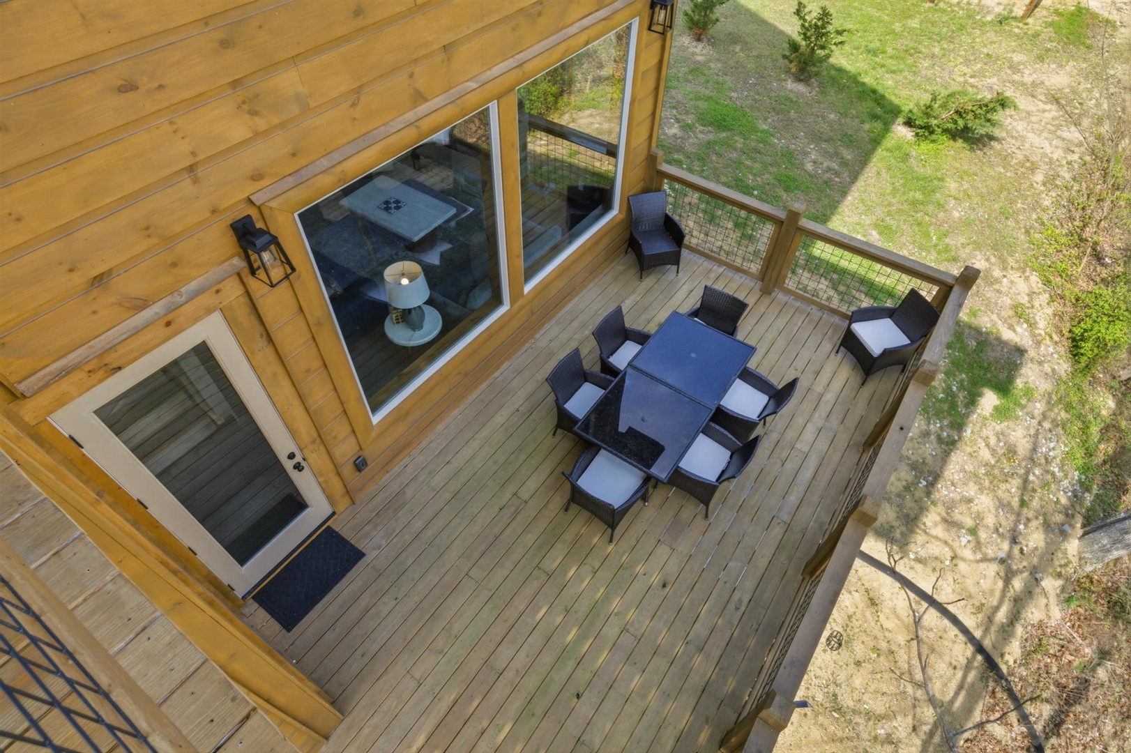 Spacious wooden deck with outdoor dining for eight, surrounded by natural garden views.