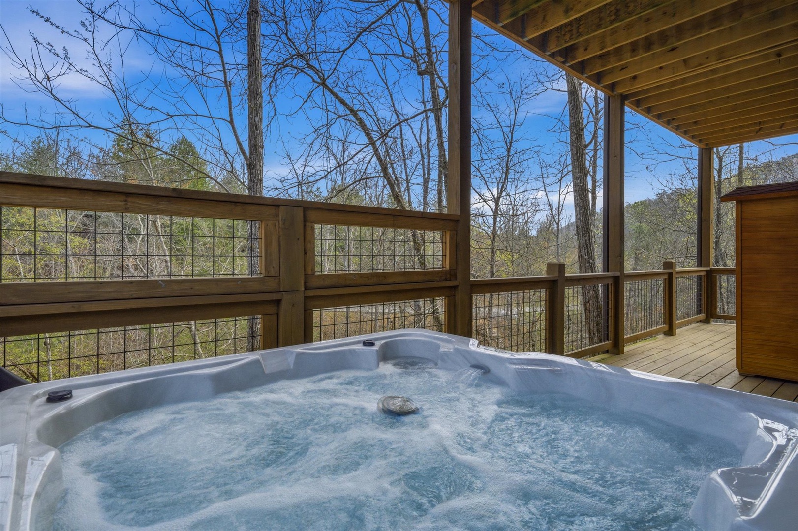 Soak in your private hot tub while surrounded by peaceful forest views from your covered deck.