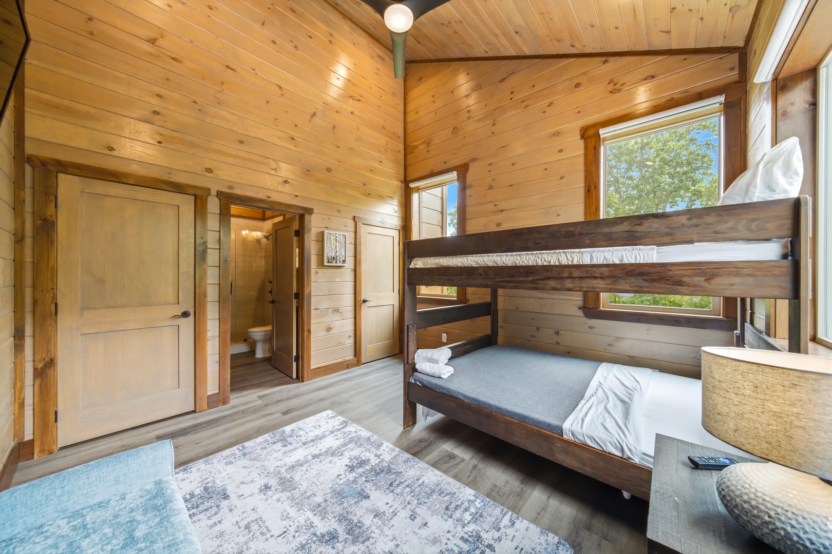 Cozy up in this charming wood-paneled bedroom with warm natural light and a bunk bed setup perfect for the kids or your travel companions. The room opens to your private bathroom and feels like a peaceful woodland retreat.