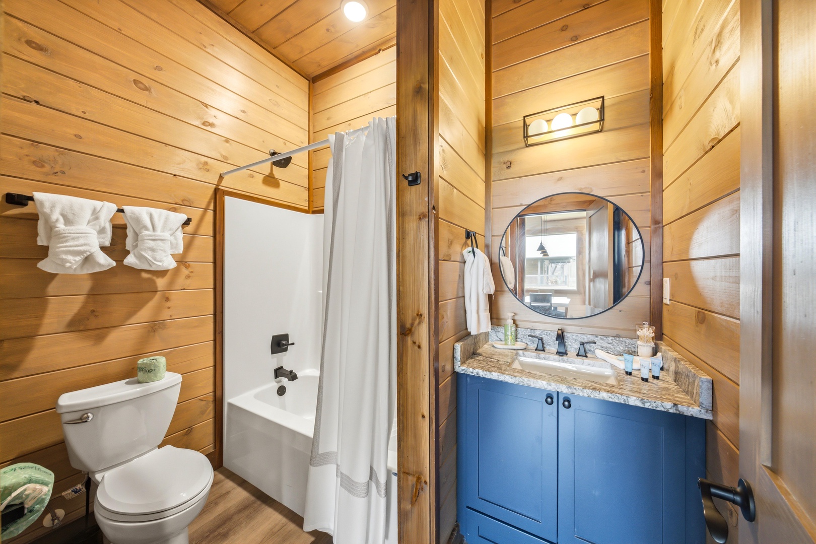 Refresh in your private bathroom with warm wood-paneled walls, a full tub and shower, and charming rustic details that make you feel right at home.