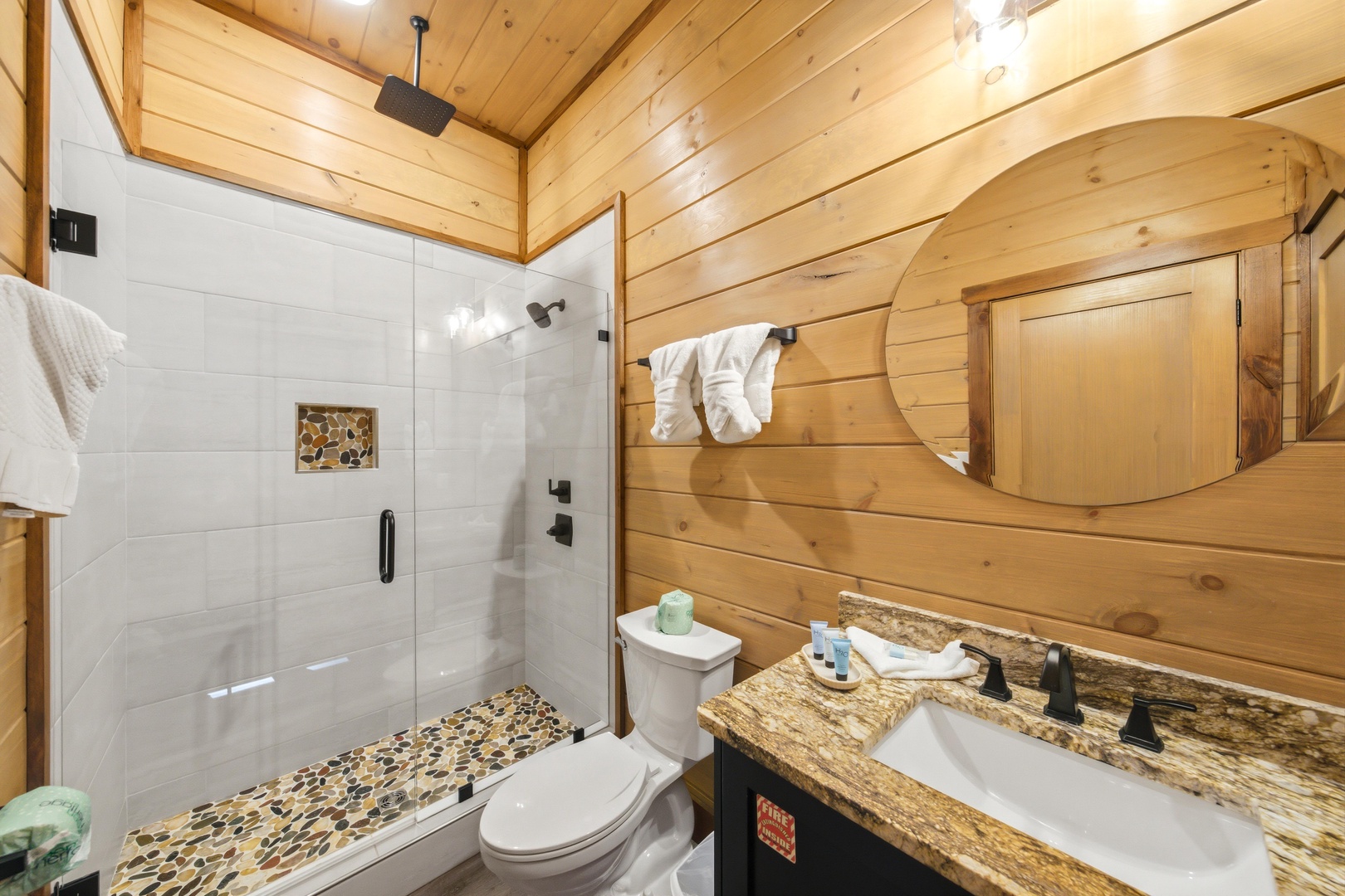 Refresh in your private bathroom featuring a spacious walk-in shower, warm wood paneling, and thoughtful touches like fluffy towels and granite countertops—all designed with your comfort in mind.