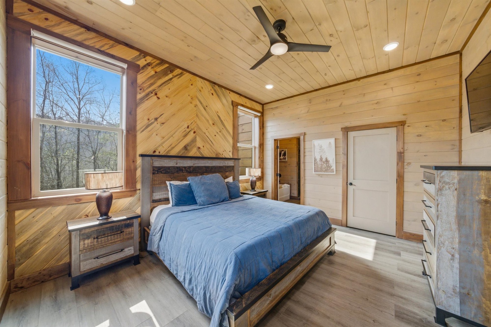 Drift off to sleep in your cozy wood-paneled bedroom, where natural light fills the space and rustic charm meets modern comfort.