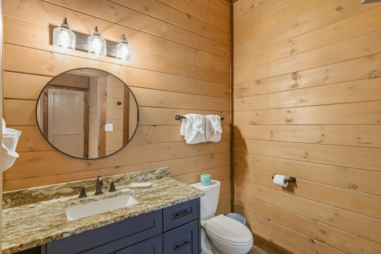Warm wood walls and granite counters create your perfect rustic retreat bathroom with modern comfort.