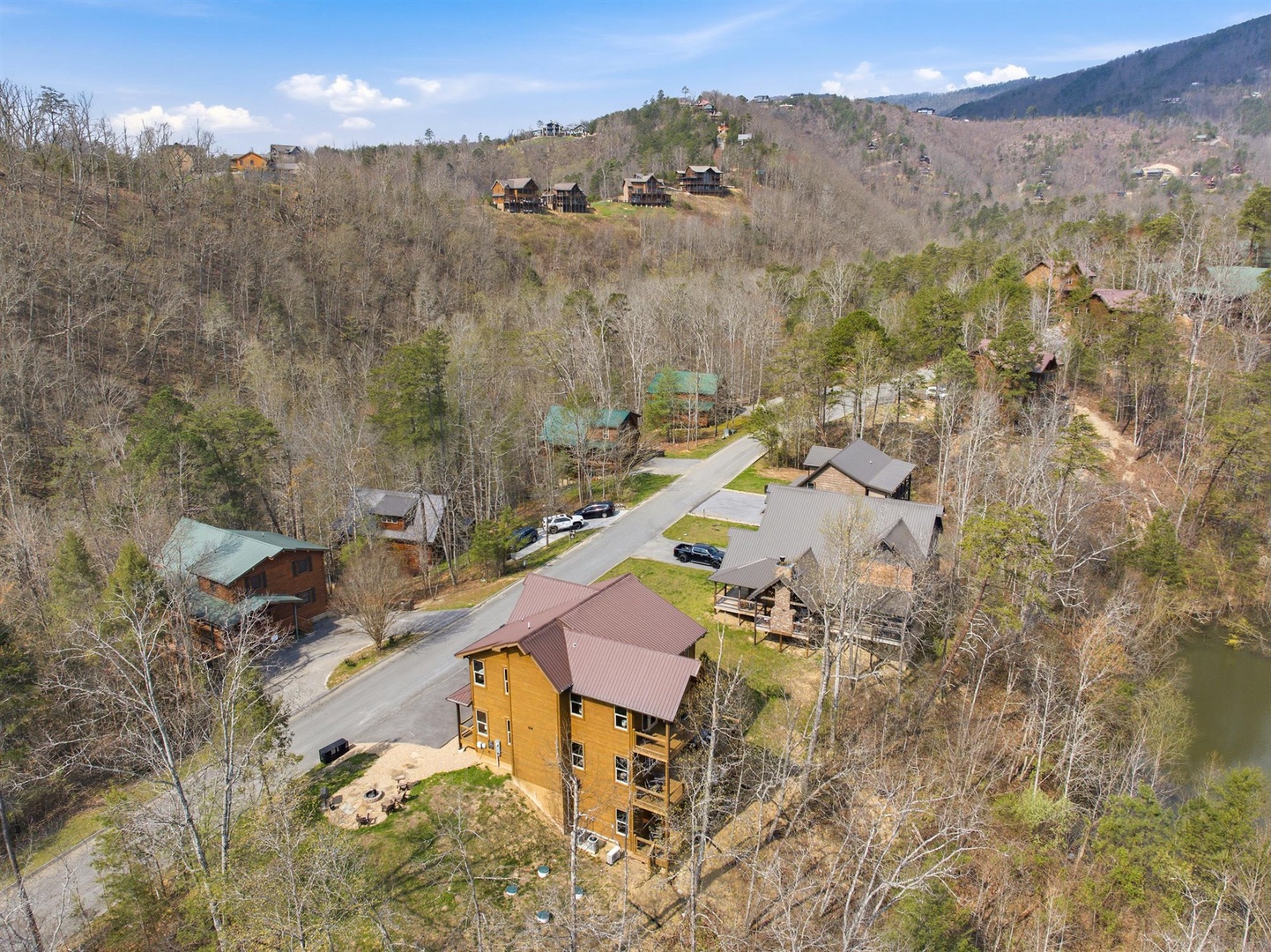 Aerial view of mountain cabin community nestled among forested hills with winding access roads and scattered vacation homes throughout the peaceful valley.