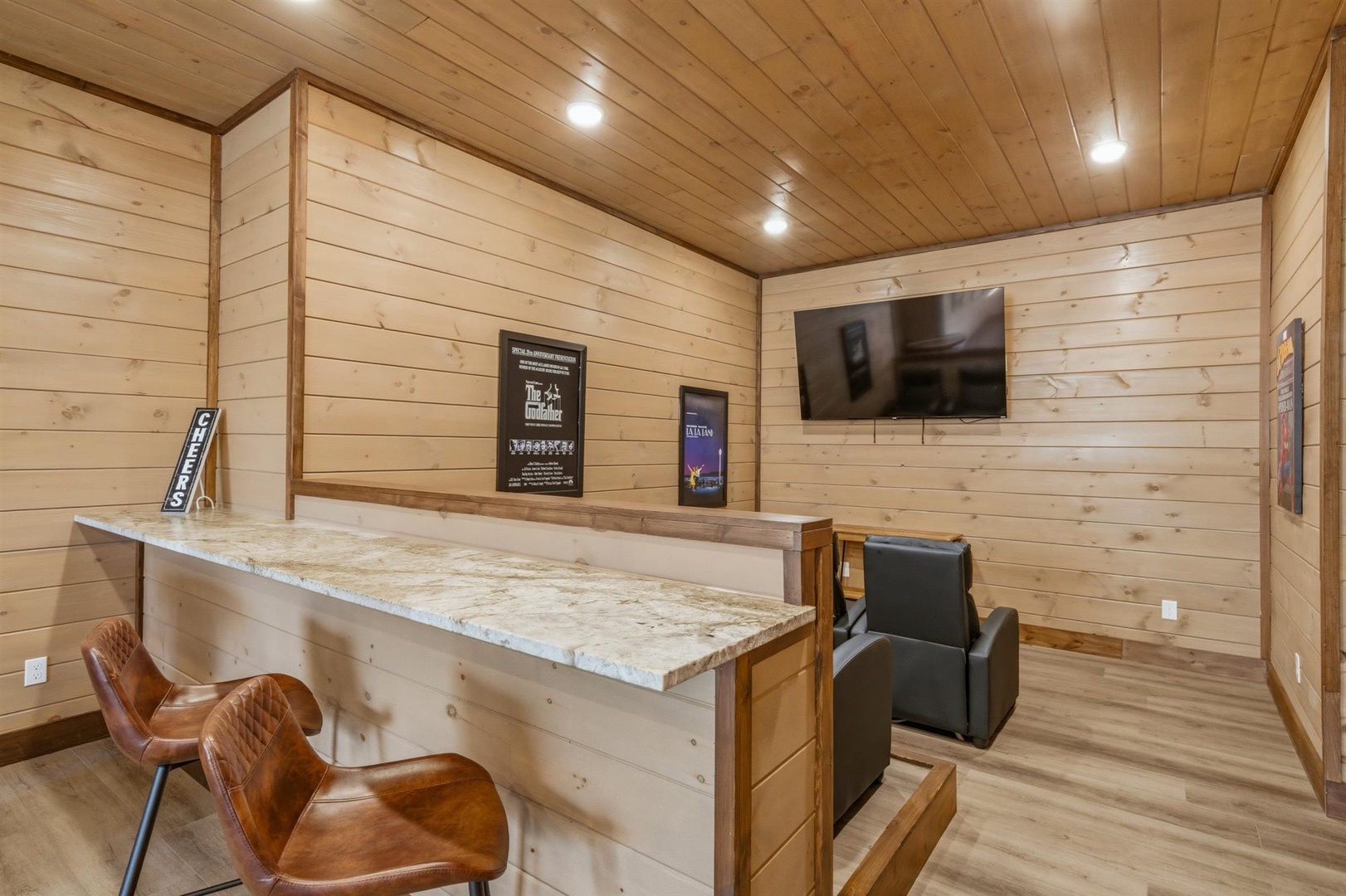 Your rustic entertainment space features warm wood walls, a granite bar counter, and cozy seating for movie nights.