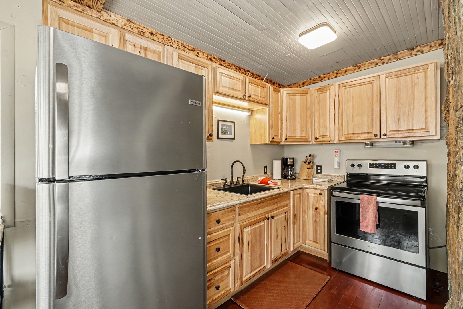Step into your cozy mountain retreat featuring handcrafted pine cabinetry with rustic live-edge accents, modern stainless steel appliances, and warm wood floors that invite you to cook and unwind in comfort.
