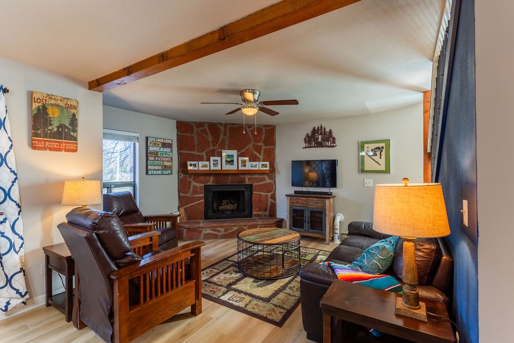Relax in your cozy living room with exposed beams, stone fireplace, and comfortable leather seating perfect for evening conversations.