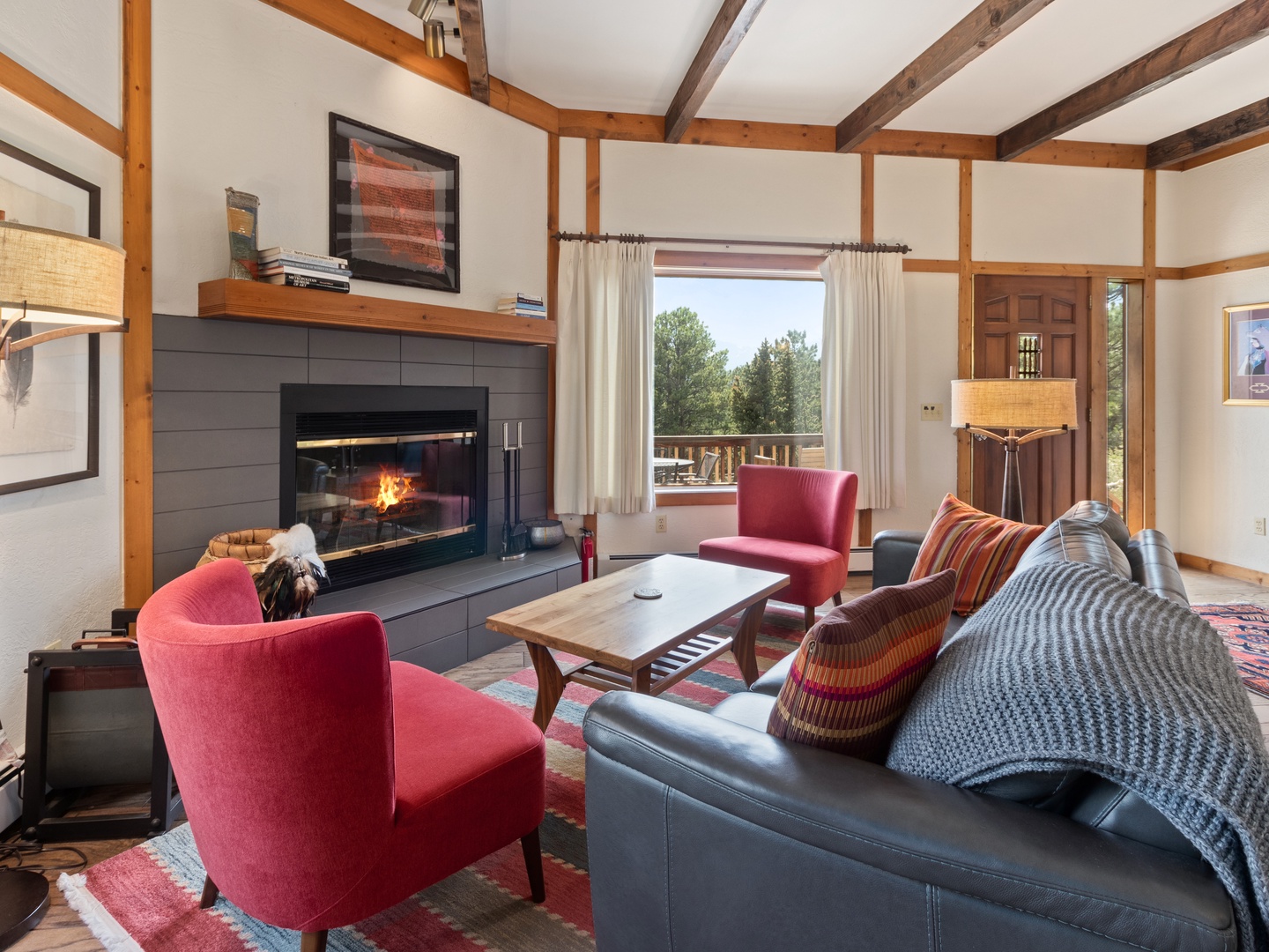 Cozy up in your inviting living room where exposed beams frame a crackling fireplace and vibrant seating creates the perfect retreat after mountain adventures.