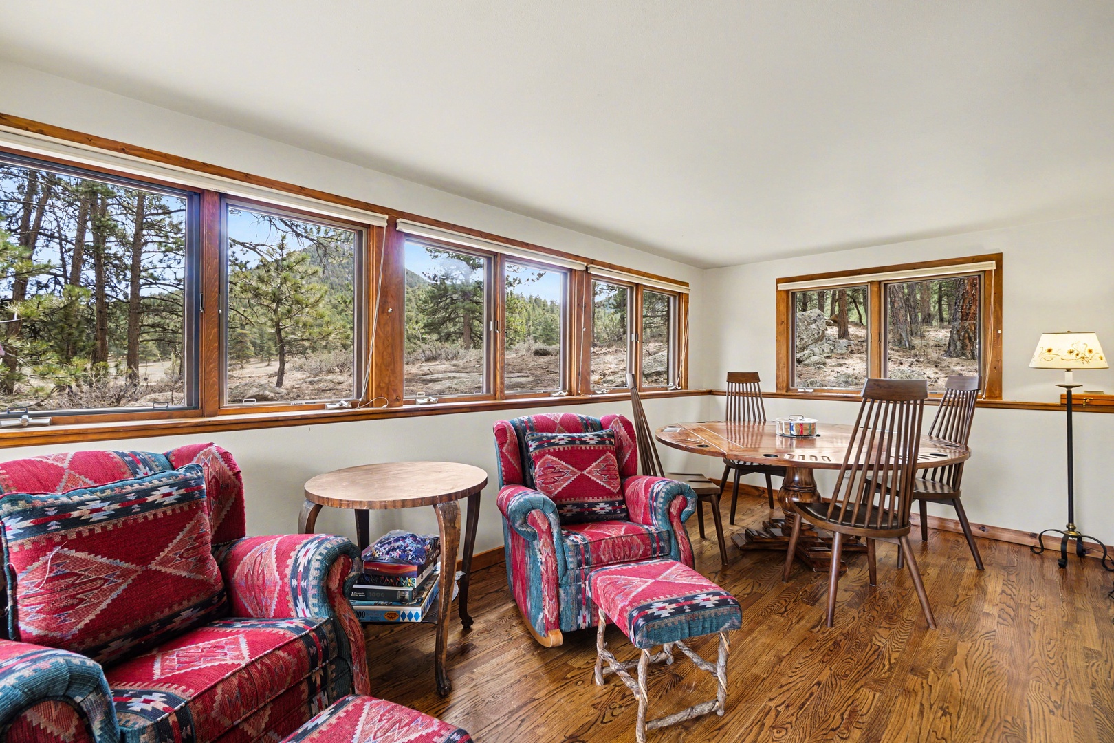 Relax in your cozy living space with vibrant southwestern textiles and panoramic forest views through expansive windows.