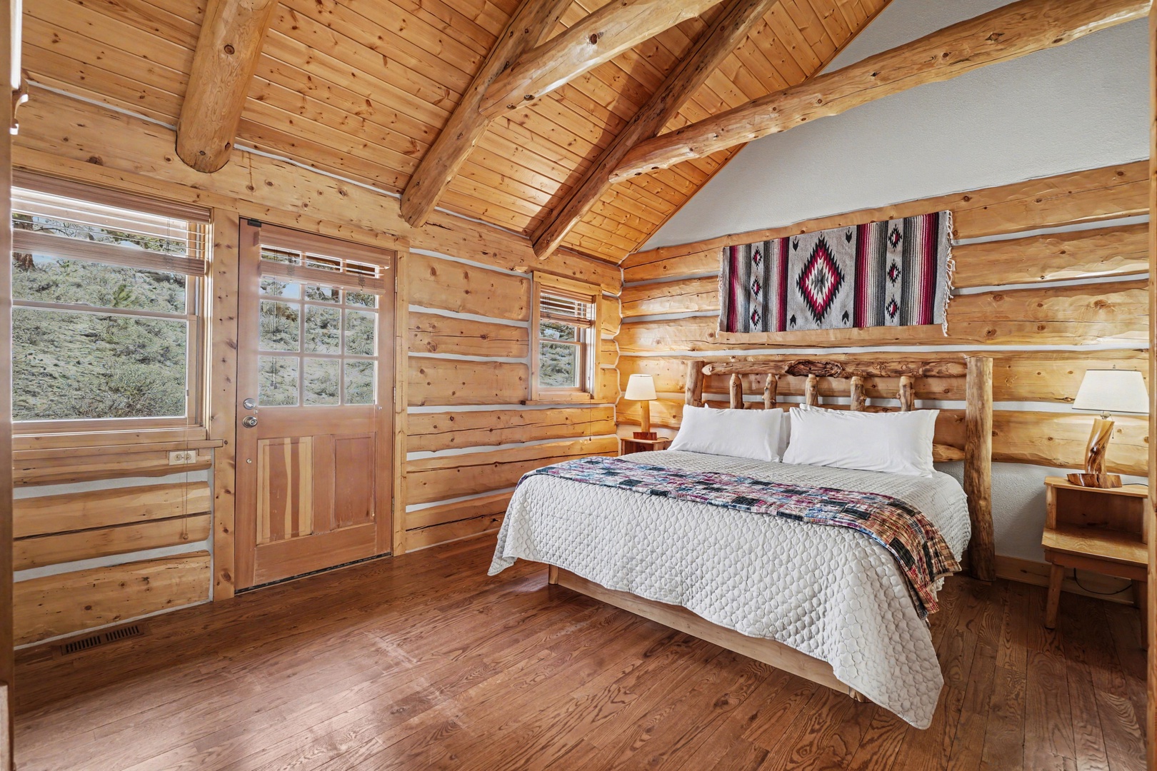 Rustic log cabin bedroom with soaring vaulted ceilings and warm wood tones creates your perfect mountain retreat.