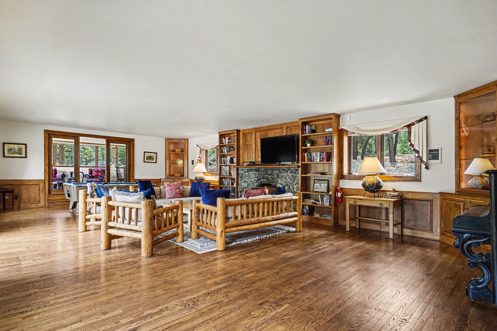 Gather around the stone fireplace in this spacious living room with rich wood floors, built-in shelving, and cozy seating perfect for relaxing.