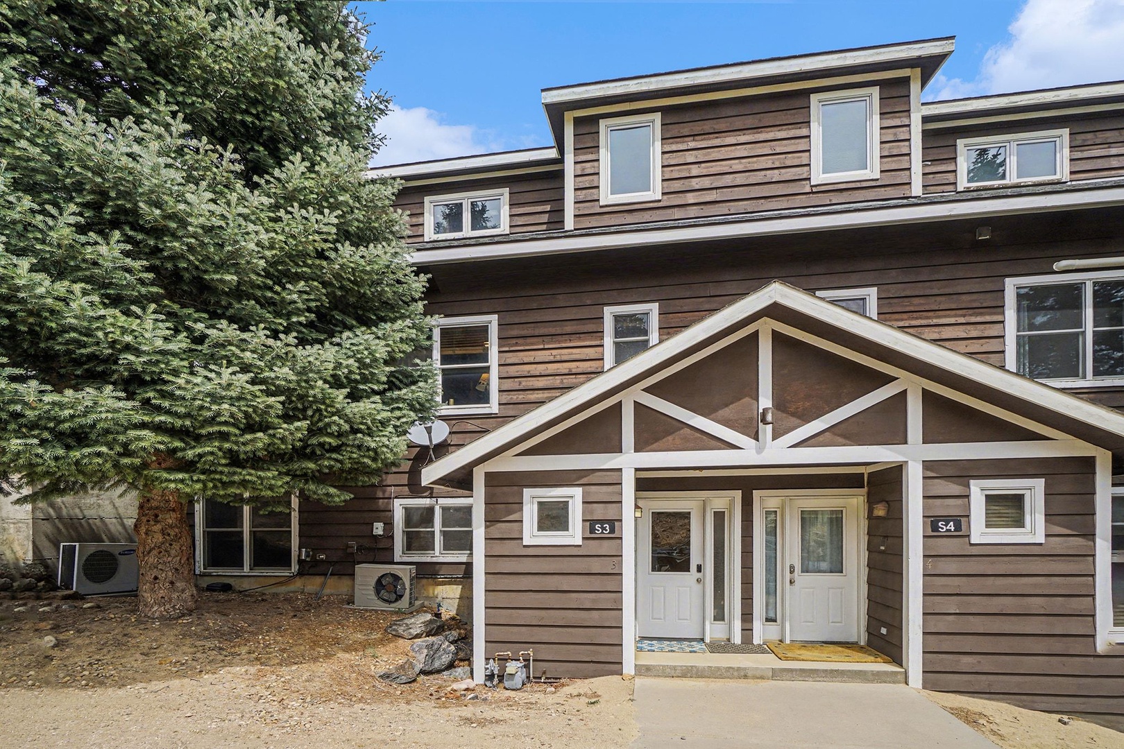 Contemporary wood-sided building with covered entrance. Nestled among mature trees in a peaceful setting.