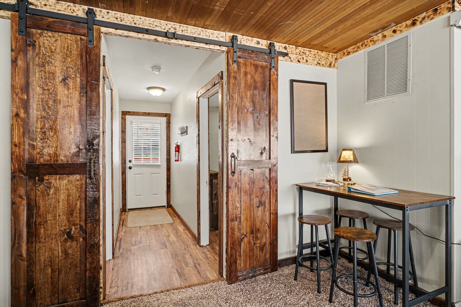 Step into your rustic retreat through charming barn doors that slide open to reveal a cozy workspace where you can plan your adventures or simply unwind with morning coffee.