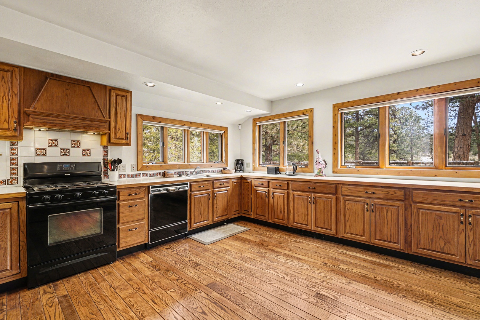 Your spacious kitchen features warm wood cabinets, modern appliances, and large windows overlooking peaceful trees.