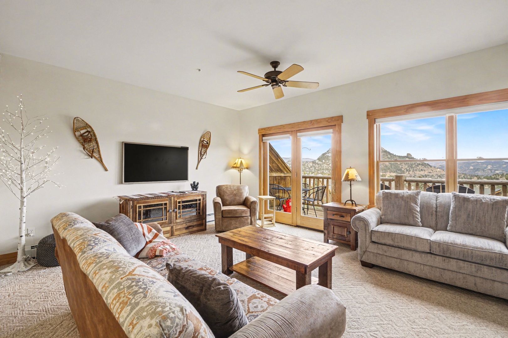 Unwind in your cozy living room with mountain views streaming through floor-to-ceiling windows, complete with plush seating and rustic charm.
