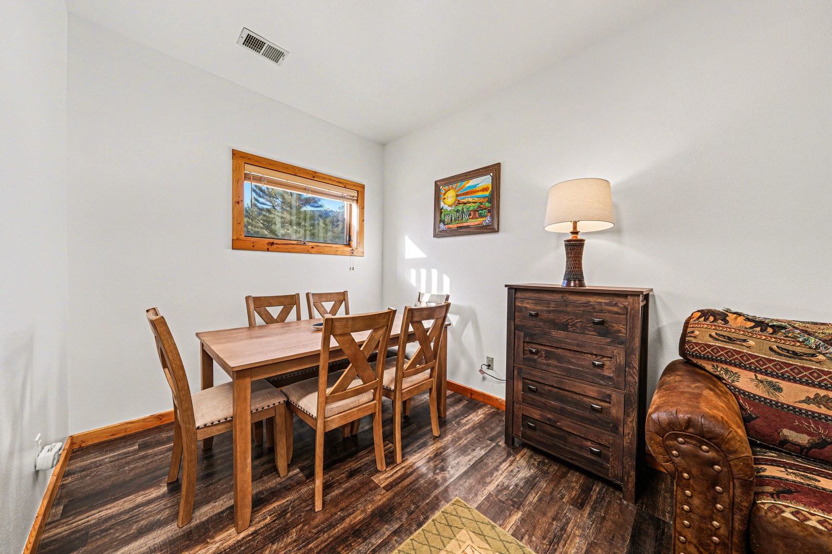 Gather around your warm wooden dining table for memorable meals together in this cozy, sunlit space.
