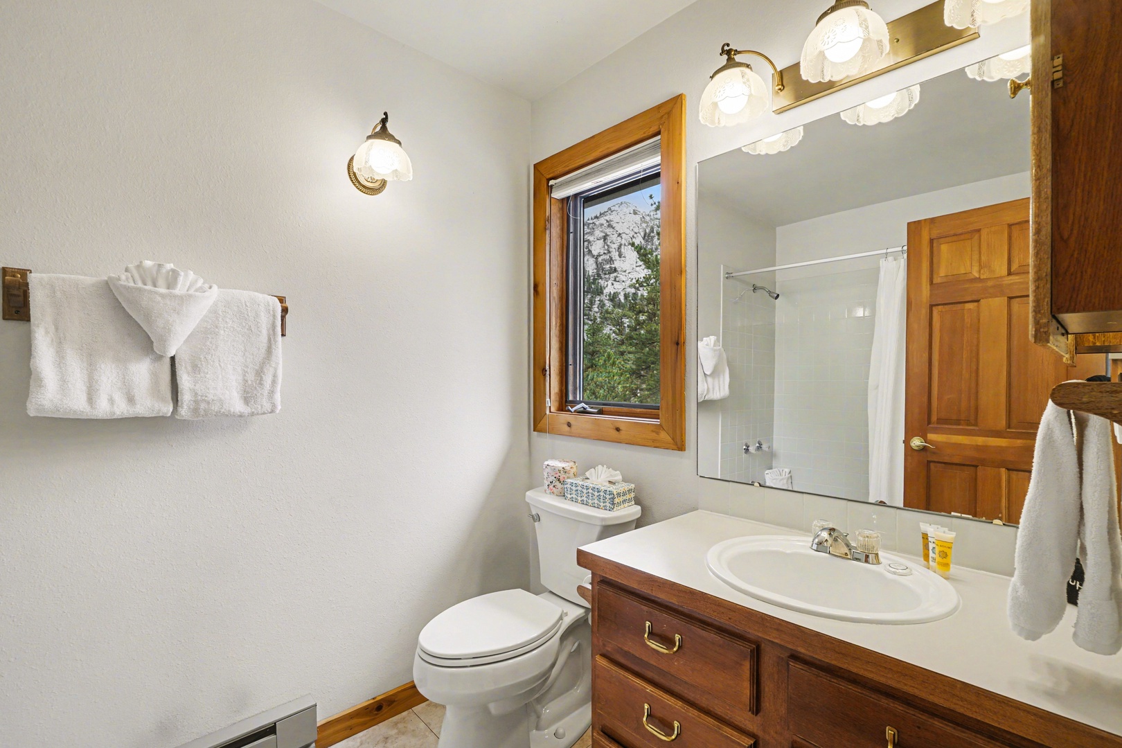 Refresh in this bright bathroom with warm wood accents, modern fixtures, and scenic mountain views through your private window.