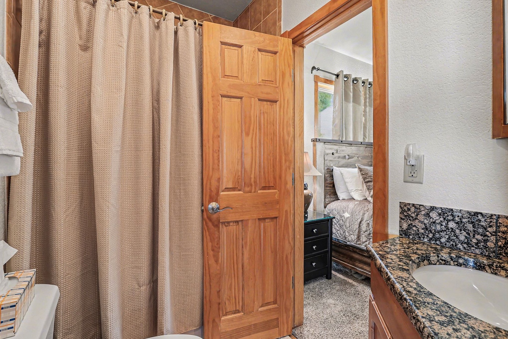 Full bathroom features granite countertops, warm wood accents, and a convenient shower-tub combo for ultimate comfort.
