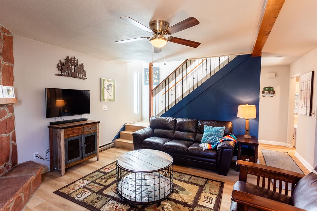 Relax in your cozy living room with leather seating, fireplace warmth, and rustic charm beneath exposed beams.