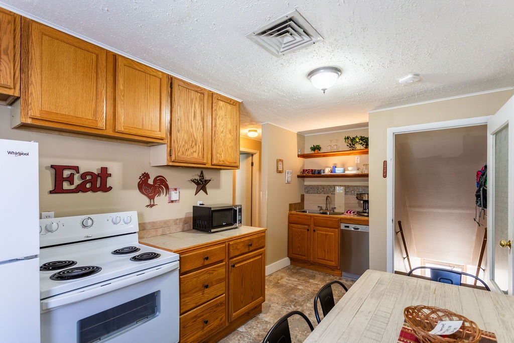 Your fully equipped kitchenette awaits with warm wood cabinets, modern appliances, and charming country touches that make cooking feel like home.