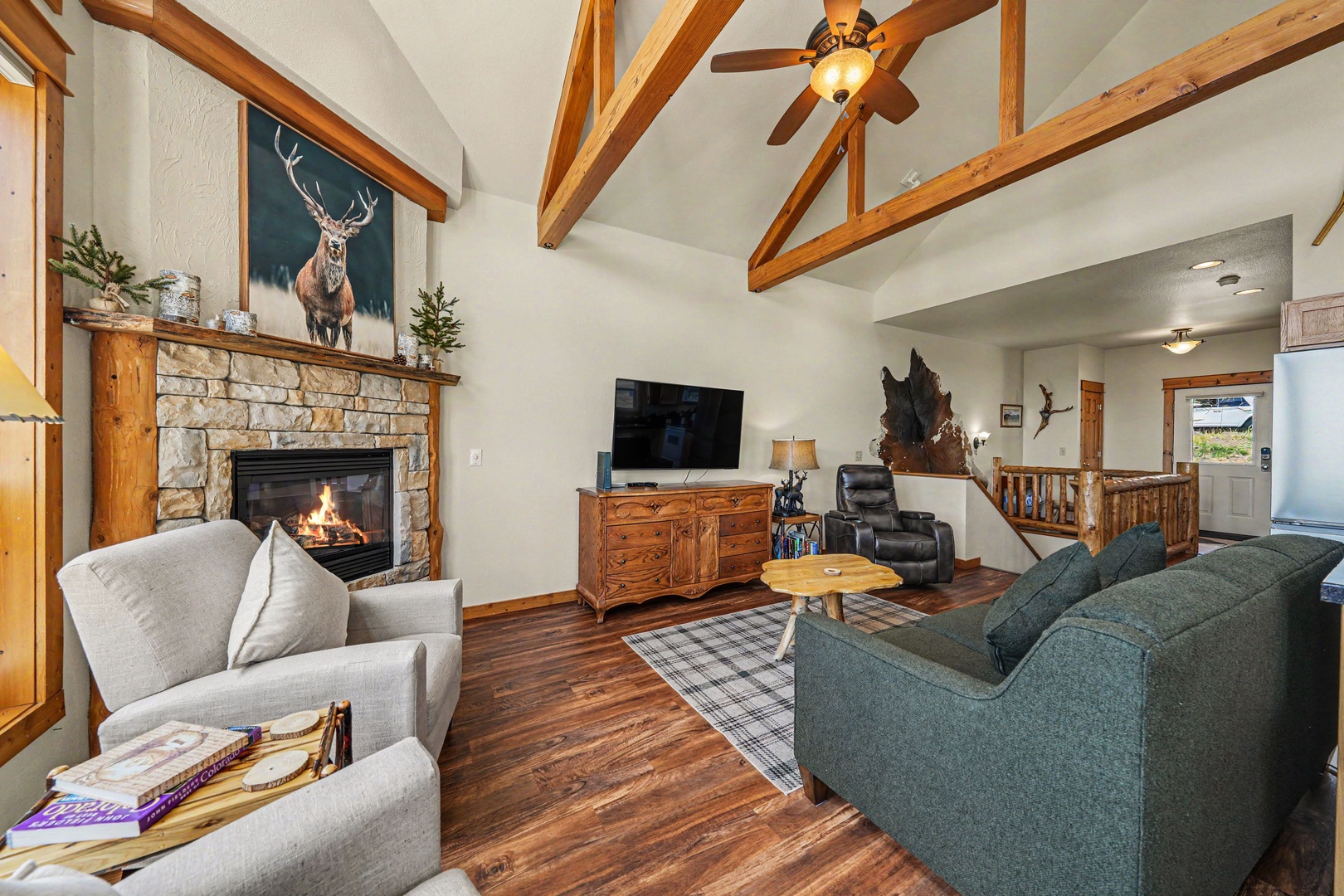 Curl up by the glowing fireplace under soaring beamed ceilings, where rustic charm meets comfort in this inviting living space perfect for your mountain getaway.