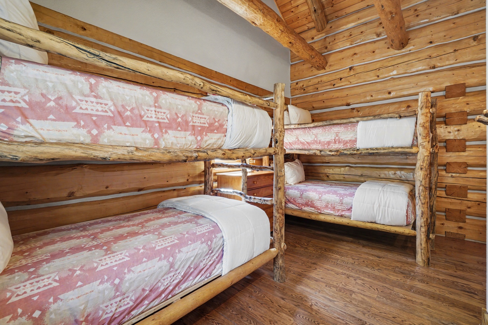 Drift off to sleep in your cozy rustic bunk room, where warm wood surrounds you and cheerful patterned bedding awaits your mountain adventures.