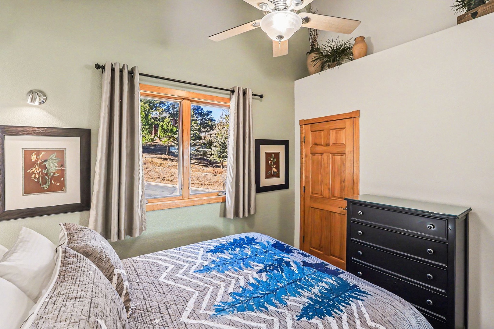 Unwind in your cozy queen bedroom sanctuary, complete with ceiling fan comfort and peaceful views of the natural landscape beyond.