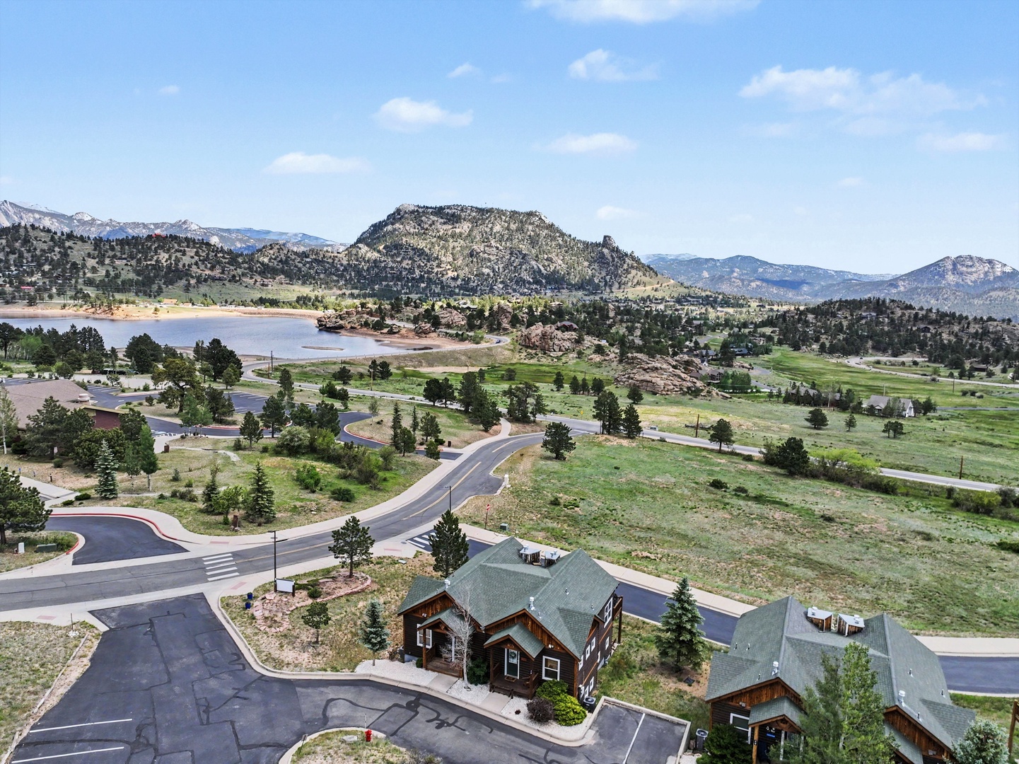 Aerial view showcasing the property nestled among mountain peaks, scenic lake, and verdant valley landscape in a peaceful natural setting.