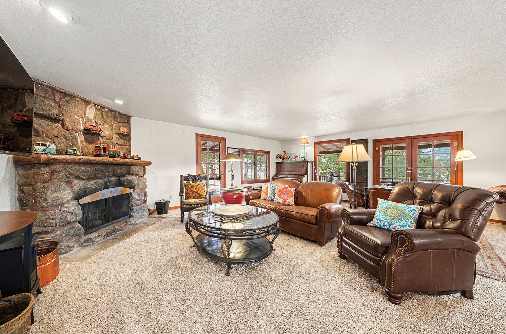 Unwind in your cozy living room with plush leather furniture, crackling stone fireplace, and warm wood accents creating the perfect mountain retreat atmosphere.