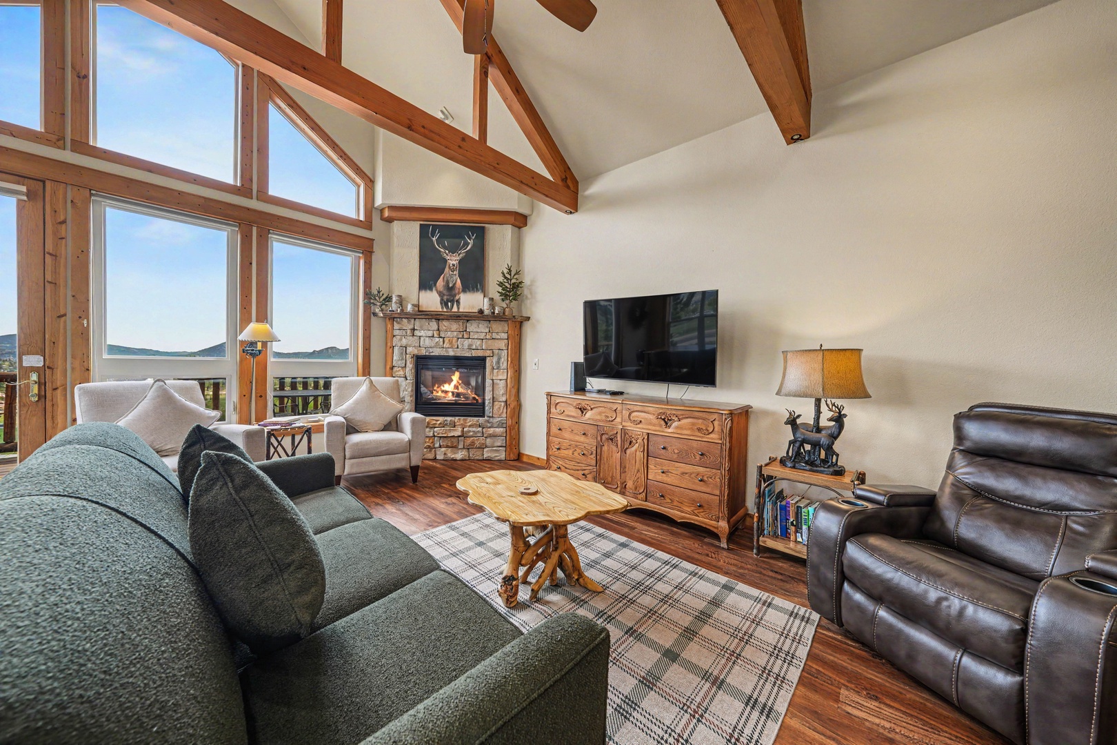 Relax in your spacious living room with soaring ceilings, exposed wood beams, and a cozy fireplace. Stunning mountain views through floor-to-ceiling windows create a peaceful retreat.