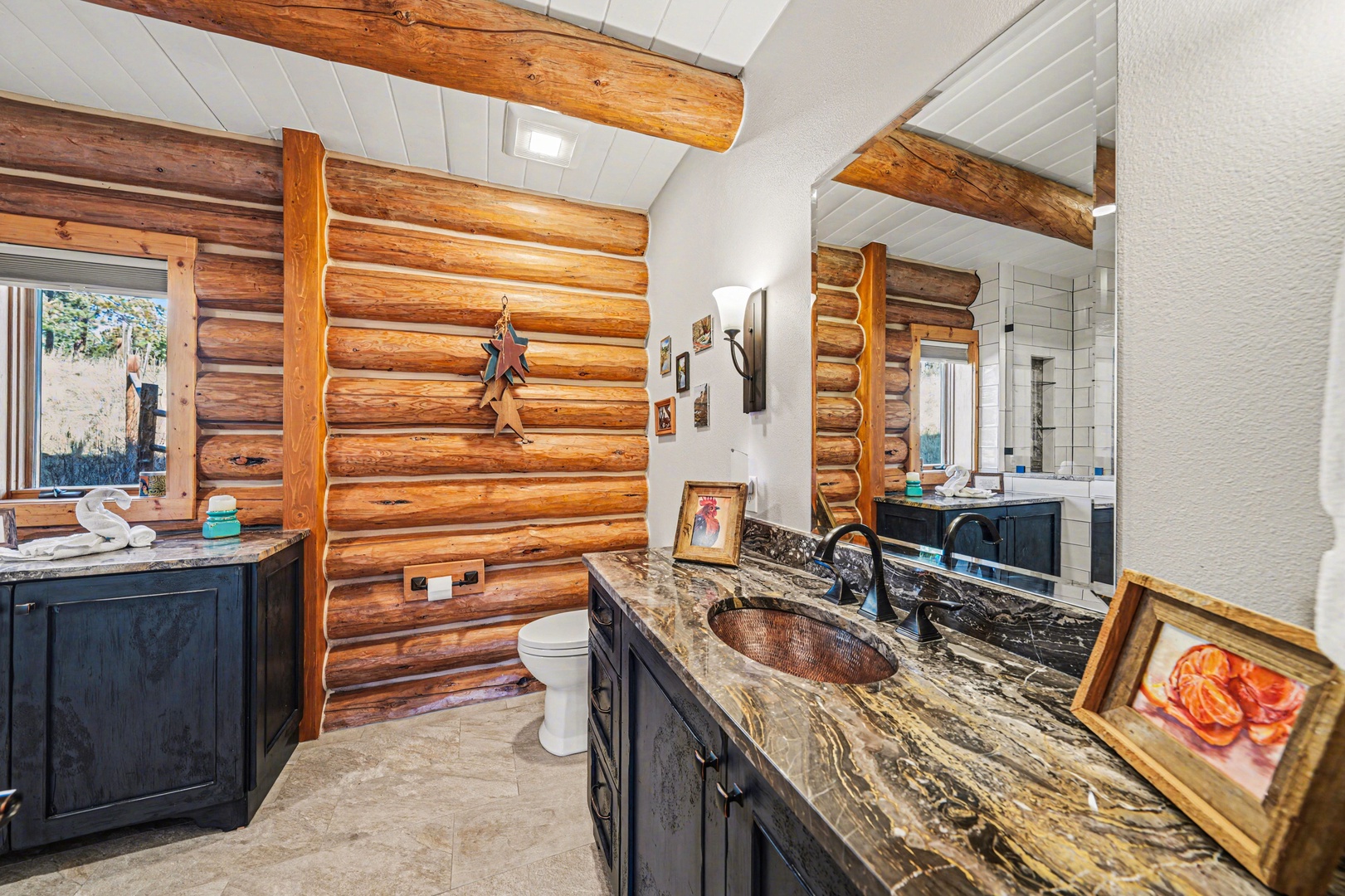 Refresh in your rustic-luxe bathroom featuring rich log walls, marble countertops, and a unique copper sink that blends mountain charm with elegant comfort.