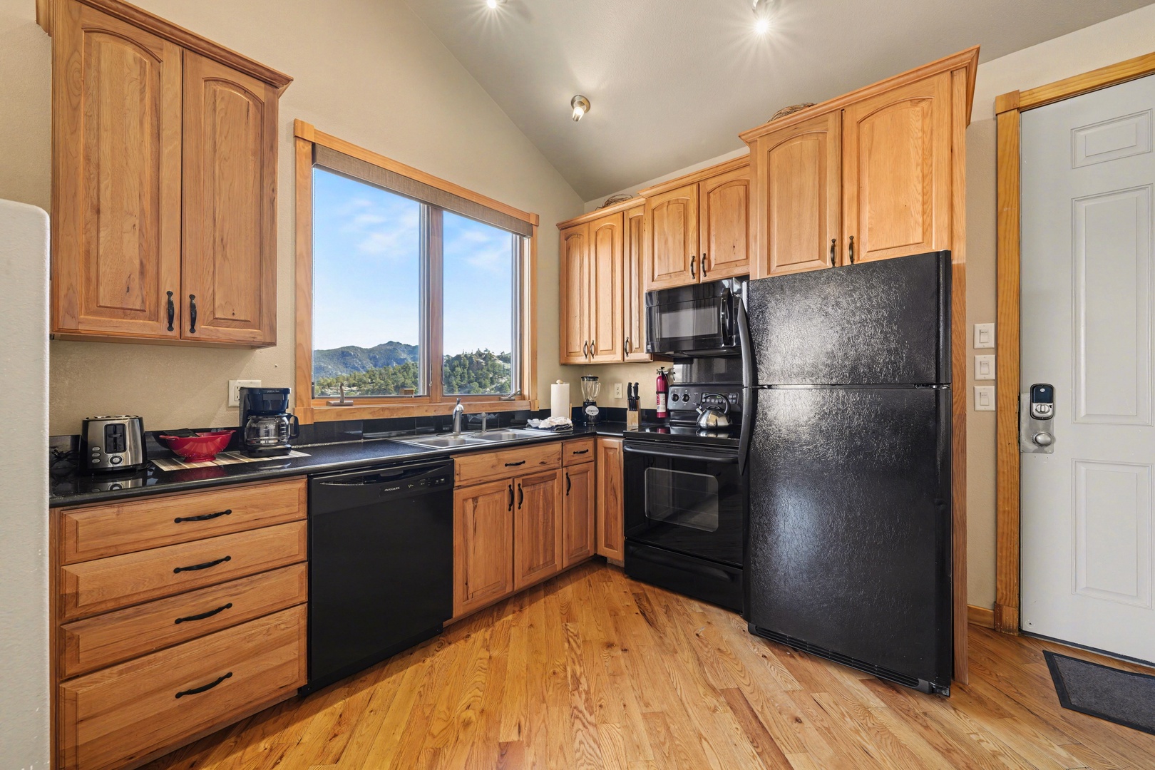 Prepare delicious meals in your fully equipped kitchen featuring warm wood cabinetry, modern appliances, and mountain views through the window.
