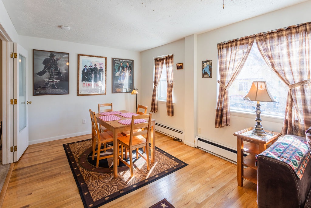 Your cozy dining space features warm wood tones, Western movie posters, and plaid curtains that frame downtown Estes Park views overlooking historic Elkhorn Avenue.