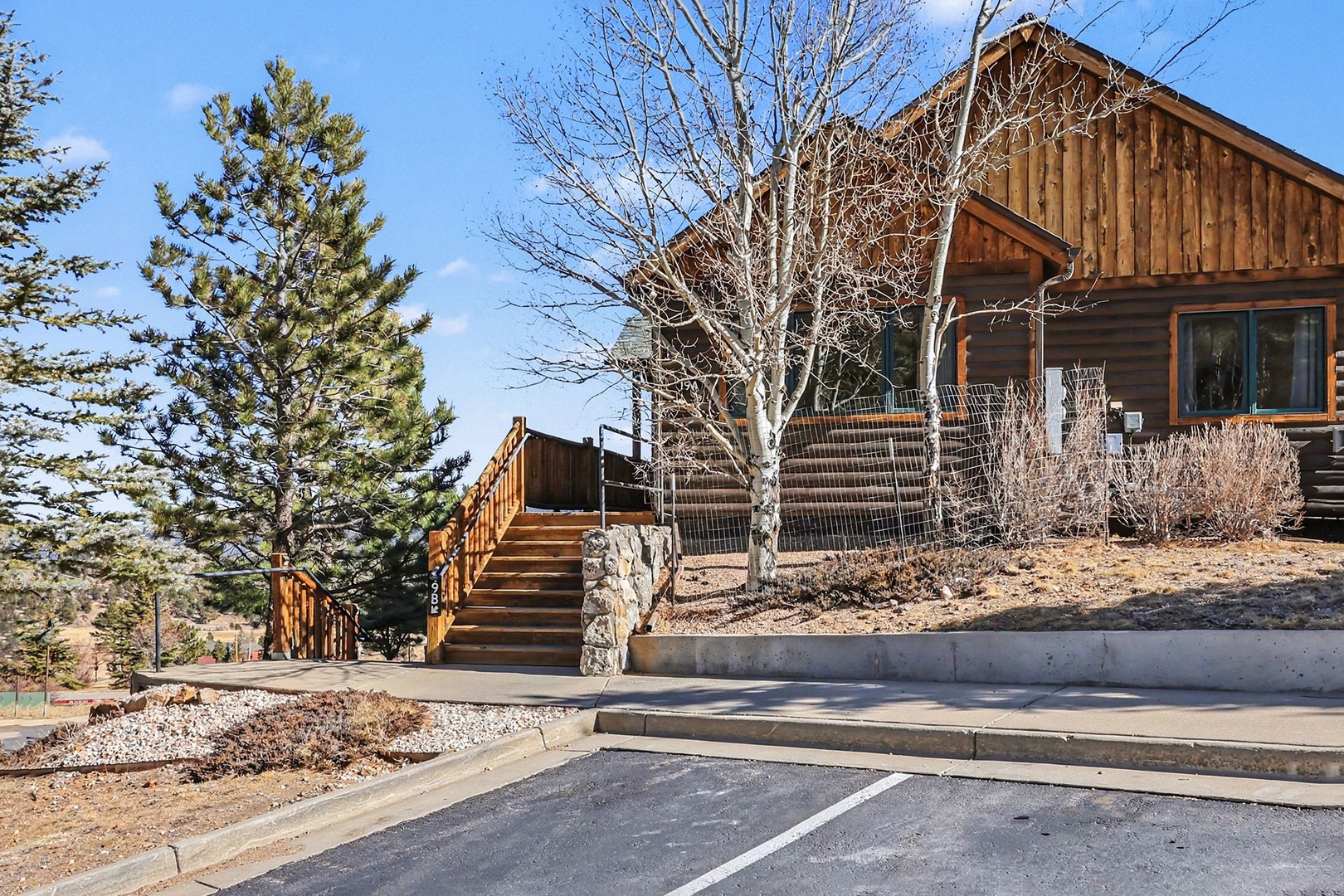 Rustic wood-sided cabin with natural stone accents and mountain landscaping creates an authentic retreat atmosphere.