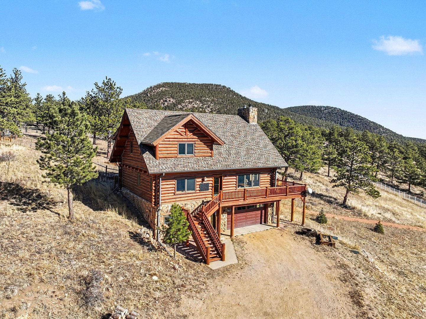 Mountain log cabin retreat surrounded by pine trees and rolling hills, offering peaceful countryside escape with spacious outdoor decking.