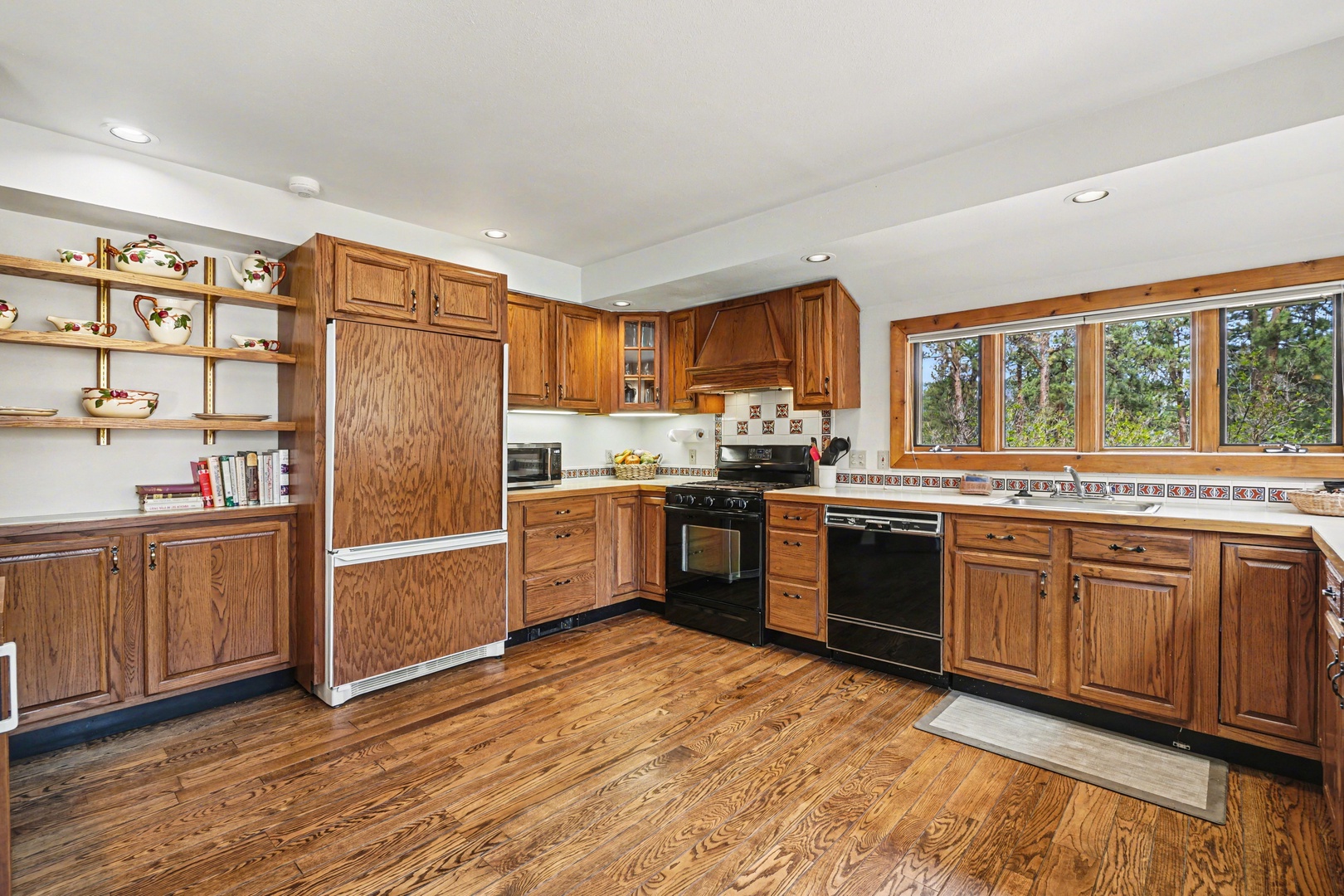 Your spacious kitchen features warm oak cabinets, modern appliances, and charming windows overlooking peaceful trees.