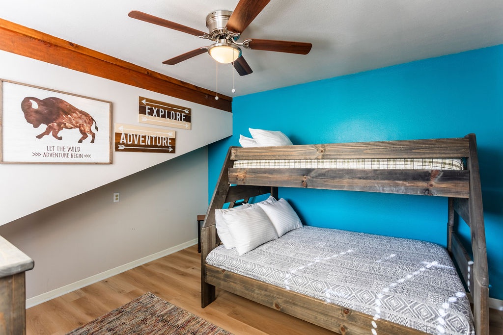 Your adventure awaits in this cozy bunk room where rustic wood meets vibrant blue walls, perfect for family getaways.