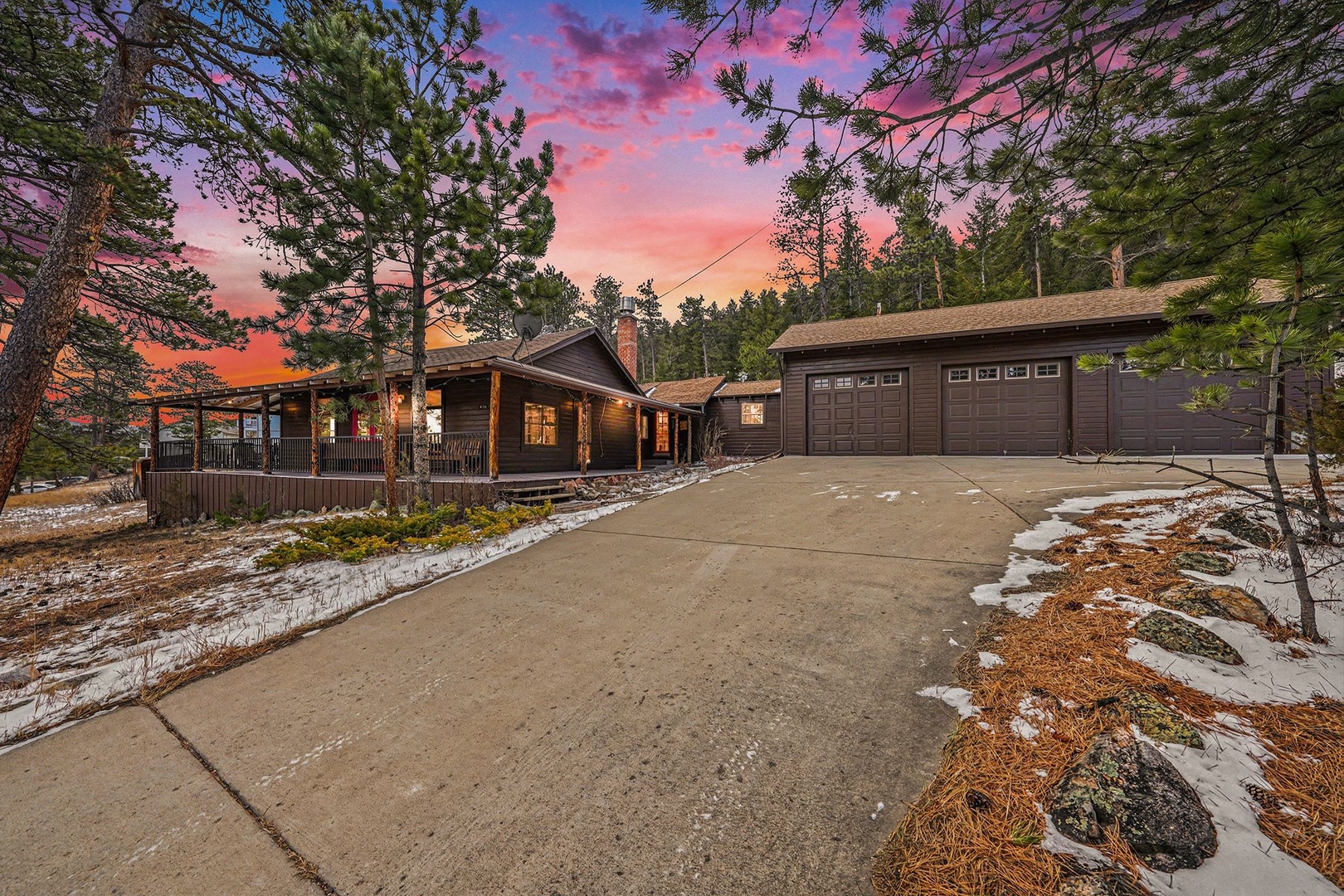 A stunning mountain retreat surrounded by towering pines, with a dramatic pink-orange sunset creating the perfect backdrop for your forest getaway.