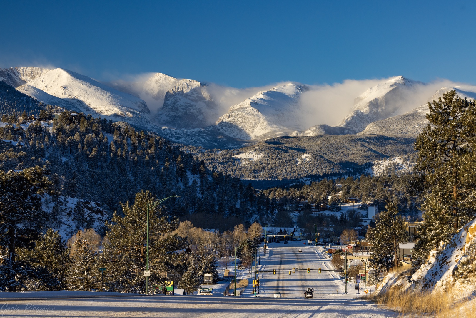 Snow-capped mountains create a dramatic backdrop for this mountain town, with winter roads leading through the scenic valley.