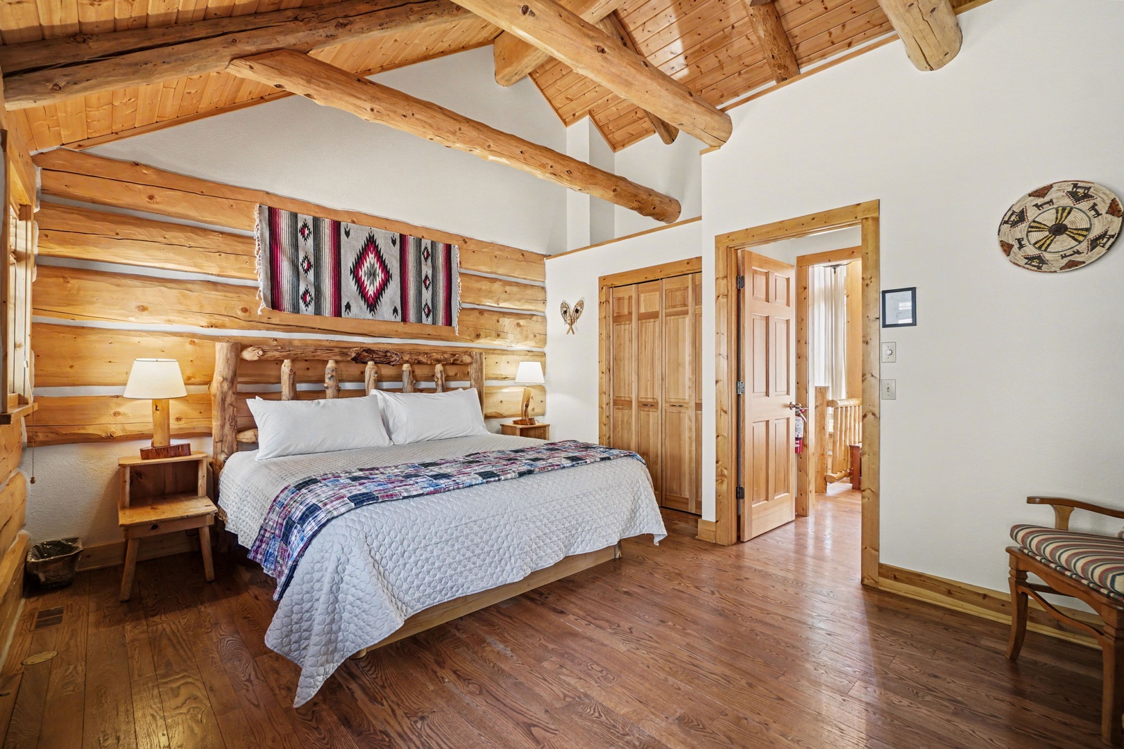 Your cozy bedroom features rustic log walls, exposed beams, and southwestern charm with handwoven textiles above your comfortable bed.