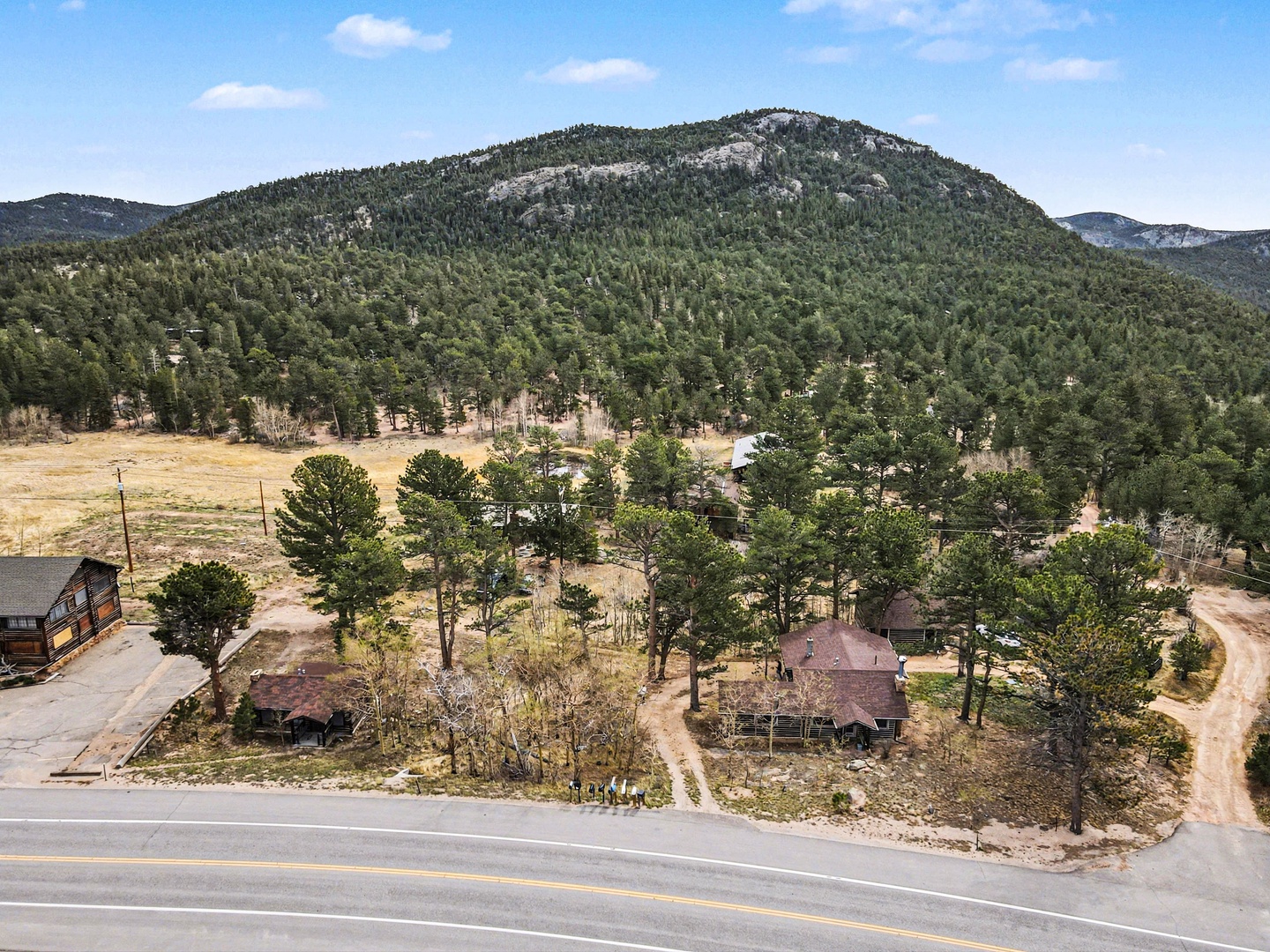 Aerial view showcases the property nestled in forested mountains with rural charm and natural beauty surrounding the area.