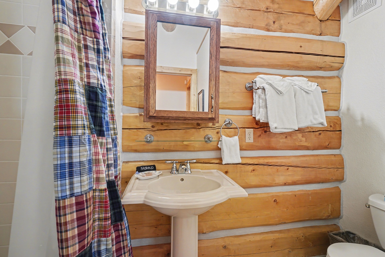 Rustic charm meets modern comfort in your private bathroom with warm log cabin walls and fresh towels.