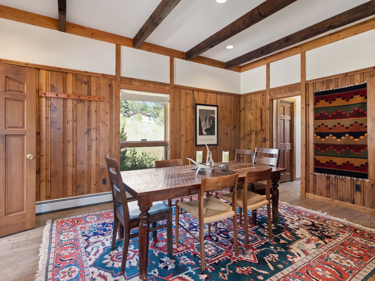 Gather around this rustic wooden dining table where exposed beams frame your meals and colorful textiles add warmth to every shared moment.