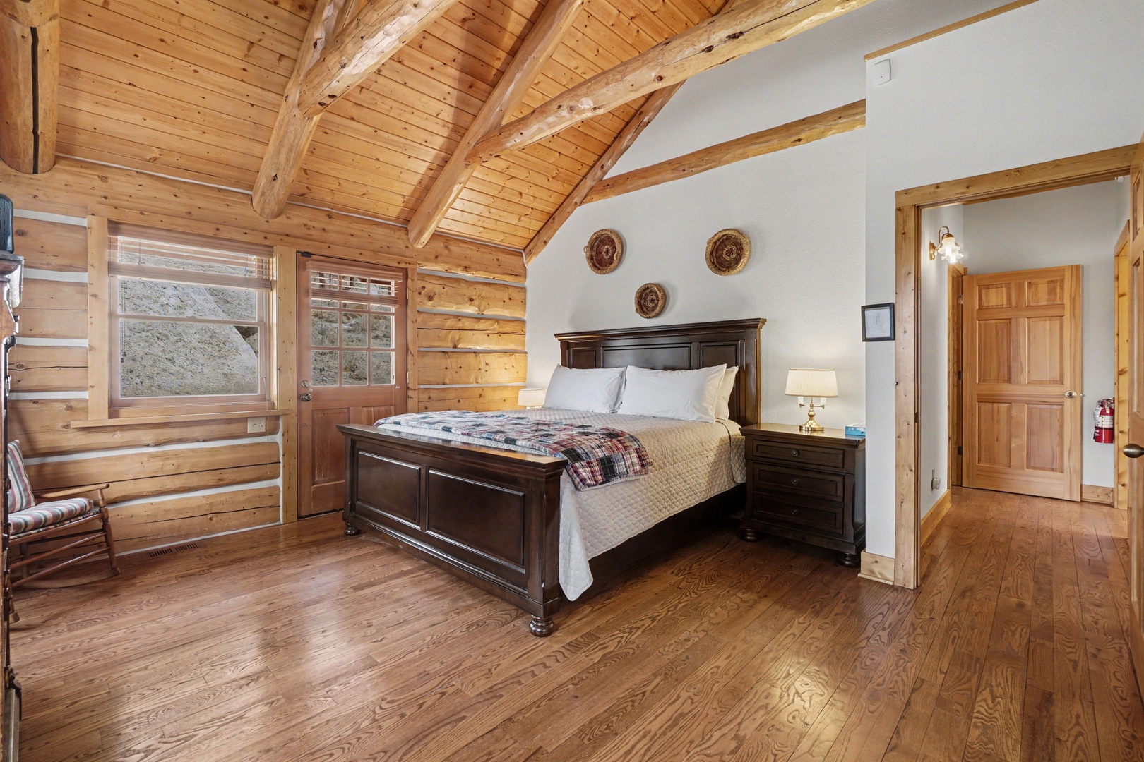 Rest peacefully in your mountain cabin bedroom with vaulted wood ceilings, handcrafted beams, and a cozy plaid throw awaiting your arrival.