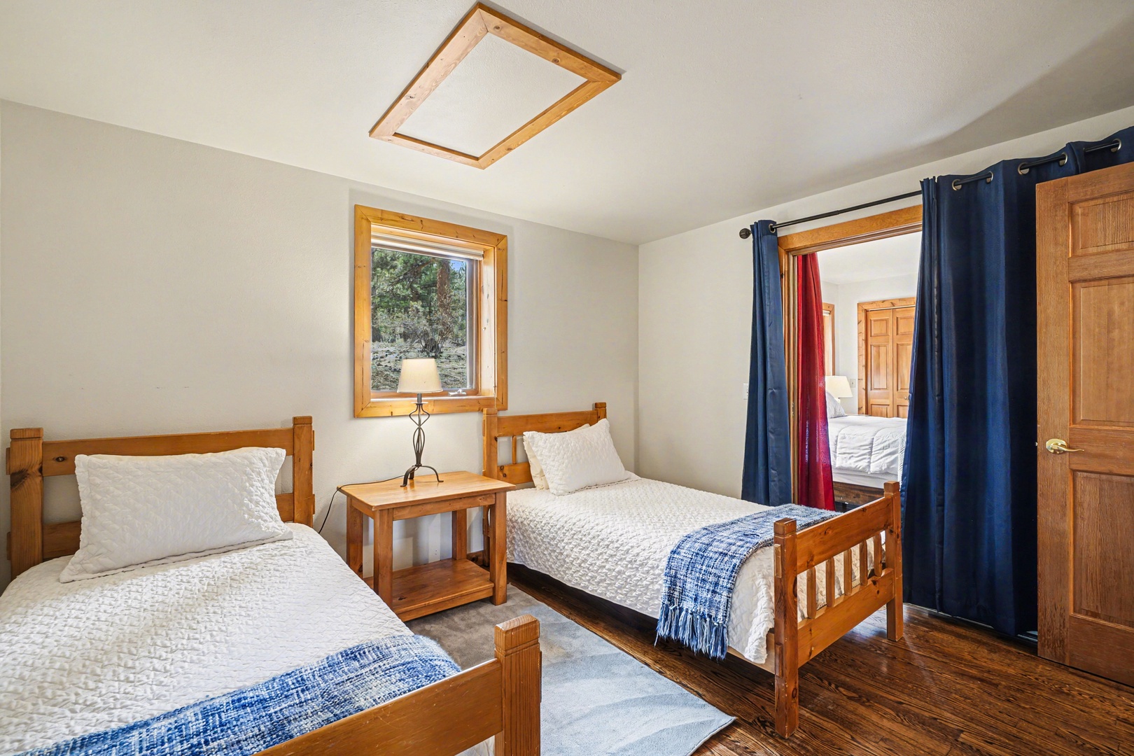 Cozy twin beds with crisp linens await you in this charming room, where natural light streams through wooden-framed windows.