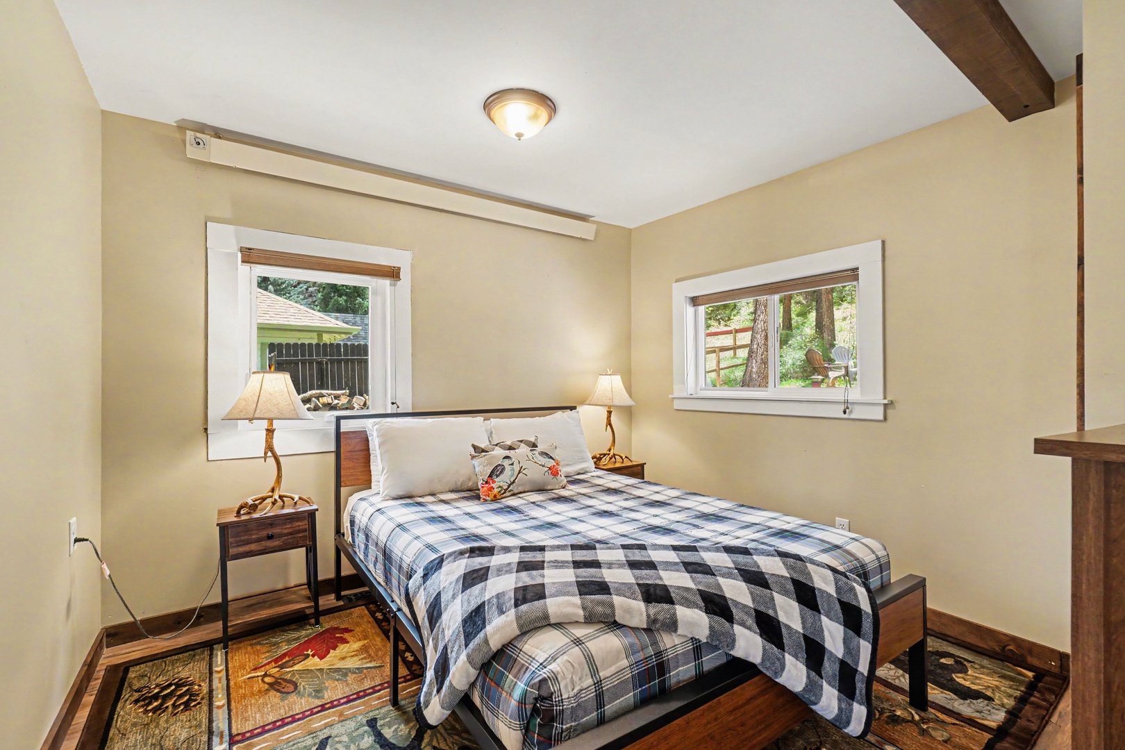 Unwind in this inviting bedroom, where soft lighting, warm wood accents, and a peaceful view through dual windows create your perfect retreat for restful nights.