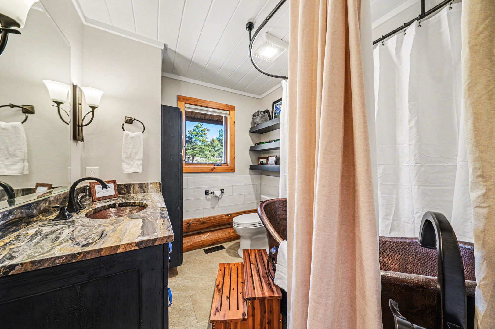 Relax in your rustic bathroom featuring a stunning granite vanity, copper sink, and charming wood accents that create a cozy mountain retreat atmosphere.