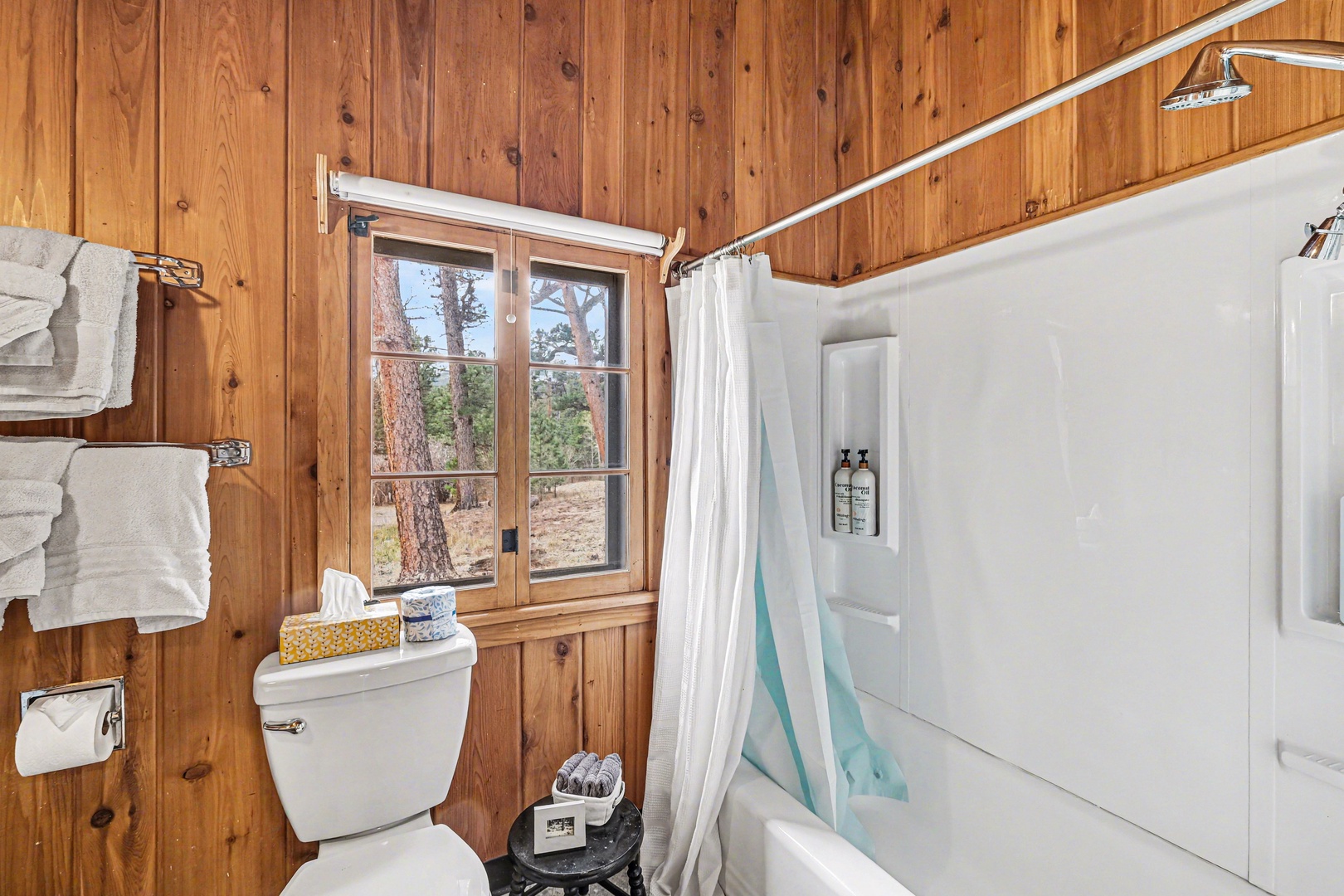 Cozy bathroom with warm wood walls, where you'll enjoy refreshing showers while gazing out at nature through the charming window.