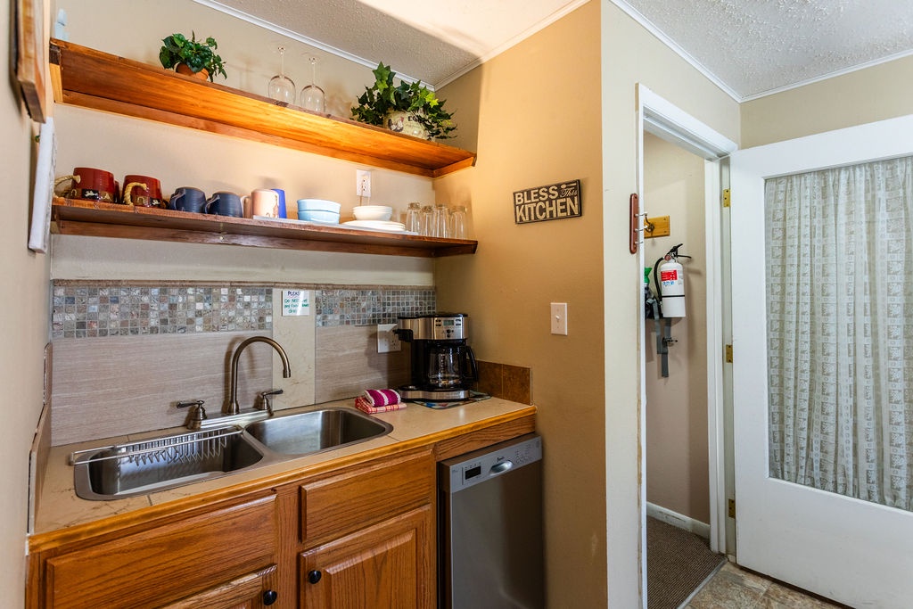 Your cozy kitchenette features warm wood cabinets, open shelving for glasses and dishes, and a coffee maker for morning brews.