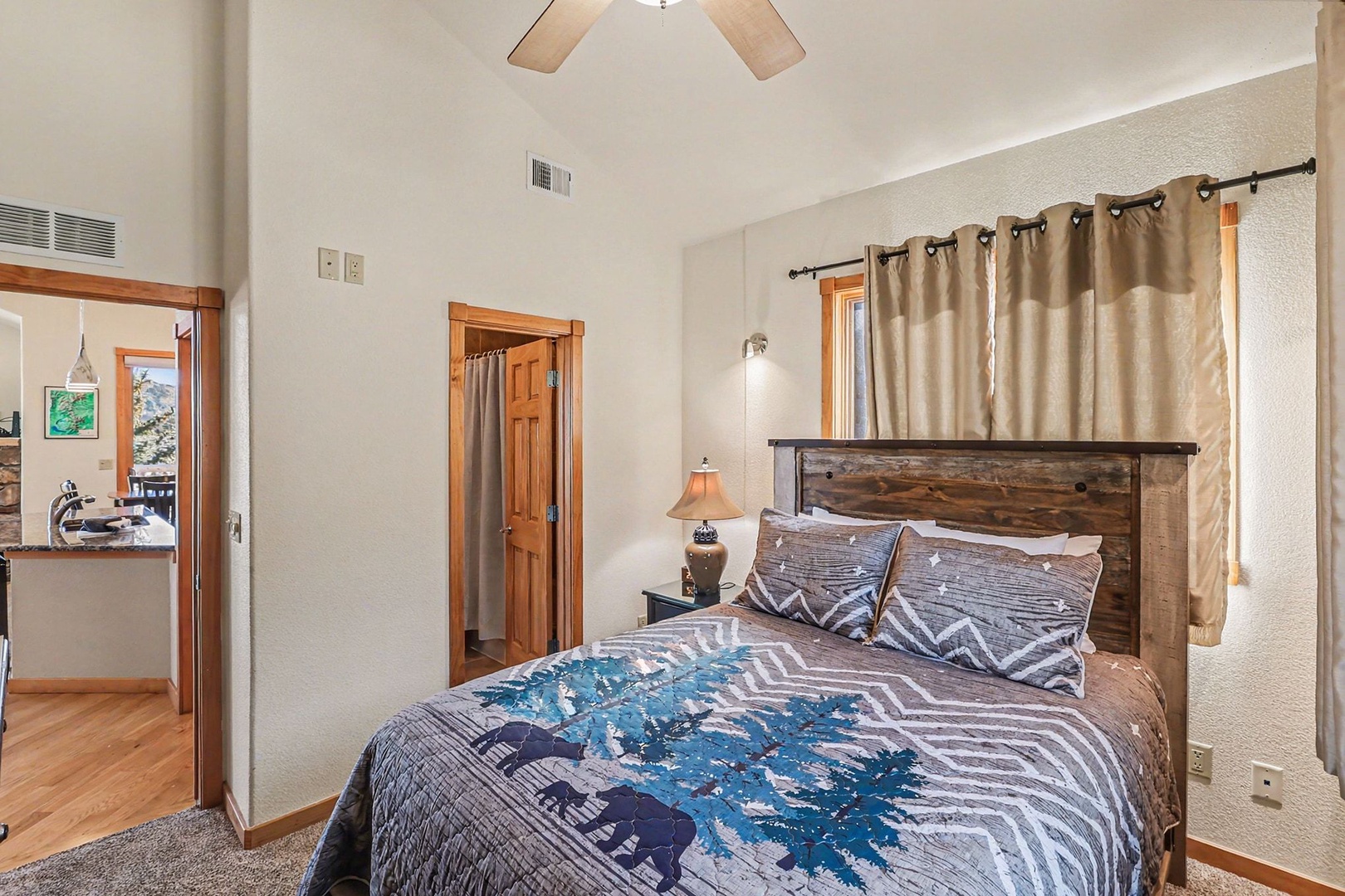 Sink into this cozy queen bedroom with rustic wood headboard, soft linens, and gentle ceiling fan breeze for your perfect mountain retreat.